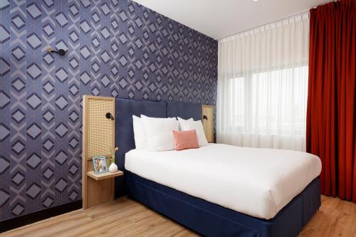 a bedroom with a large bed and a purple wall at Citadines Sloterdijk Station Amsterdam in Amsterdam