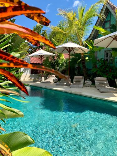 a swimming pool with chairs and umbrellas at Hari Indah Boutique Hotel & Spa in Uluwatu