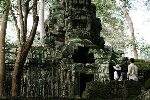 two people standing in front of a stone building at Raffles Grand Hotel d'Angkor in Siem Reap