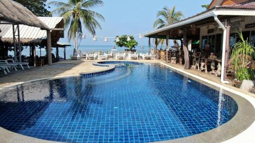 a swimming pool in front of a resort with the ocean at Lanta New Coconut Bungalow in Ko Lanta