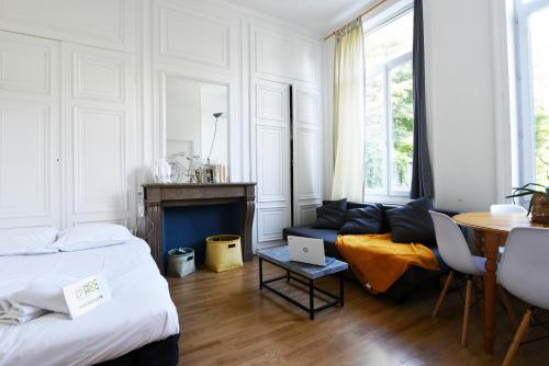 1 dormitorio con cama, sofá y mesa en NOCNOC - Le Petit National, en Lille