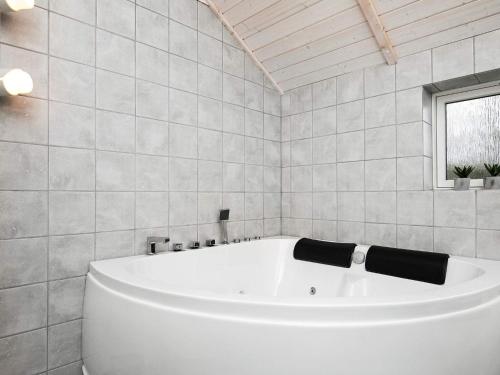a white bath tub in a white tiled bathroom at 6 person holiday home in Thisted in Thisted