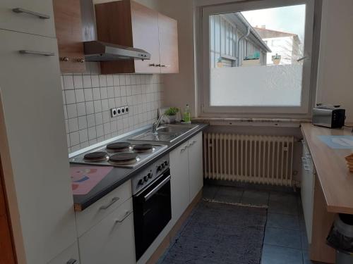 eine Küche mit einem Herd, einem Waschbecken und einem Fenster in der Unterkunft Apartment Ground Floor Laatzen in Hannover