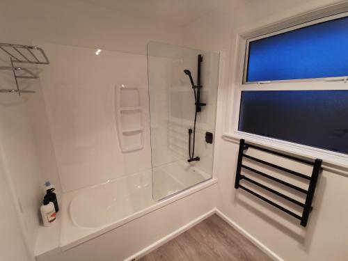 bagno bianco con doccia e finestra di Hello Seaview! 4 BRs House in Central Location! a Oamaru