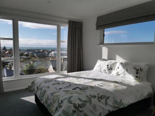 a bedroom with a bed and a large window at Hello Seaview! 4 BRs House in Central Location! in Oamaru