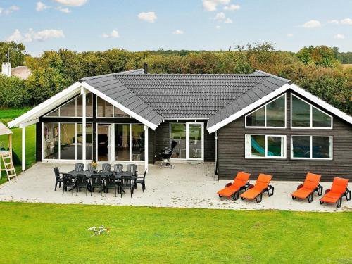 ボーゲンセにある16 person holiday home in Bogenseのパティオ(オレンジの椅子、テーブル付)が備わる家です。