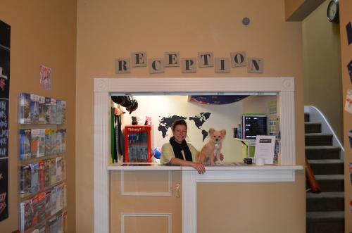 a woman is standing behind a counter with a dog at The Prince Albert Backpackers & Bar in Nelson
