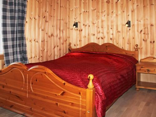 a bedroom with a wooden bed with a red bedspread at Two-Bedroom Holiday home in Gravdal 2 in Gravdal