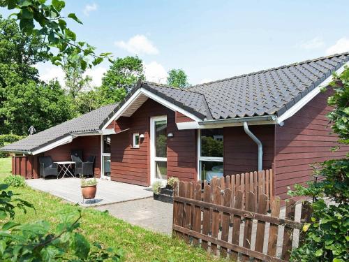 uma casa vermelha com uma cerca de madeira em frente em 8 person holiday home in Juelsminde em Sønderby