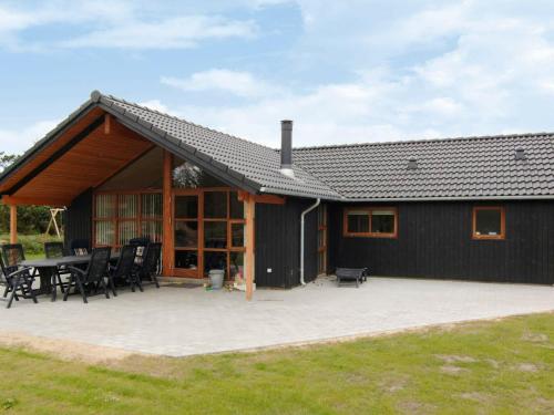 a black house with a patio and a table at 8 person holiday home in Vejers Strand in Vejers Strand