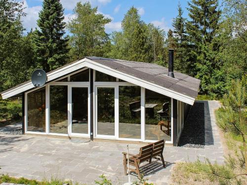 un salón acristalado con techo en un patio con banco en 5 person holiday home in Herning en Kølkær