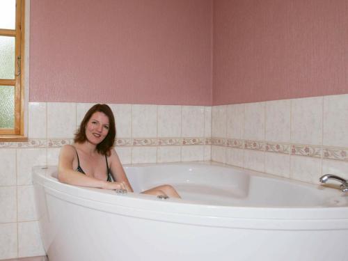 una mujer está sentada en una bañera en 8 person holiday home in R dby, en Kramnitse