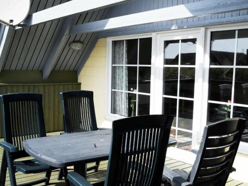 una mesa de madera y sillas en un porche con ventana en 6 person holiday home in Ringk bing, en Klegod