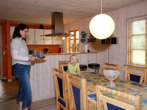 a woman standing next to a little girl sitting at a table at 8 person holiday home in R dby in Kramnitse