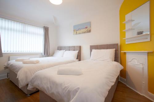 two beds in a room with white sheets at Spacious Stylish Residence in Leeds