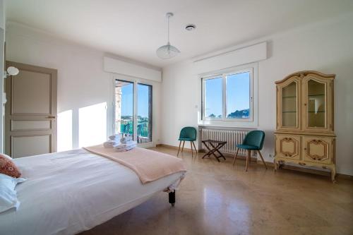 - une chambre blanche avec un grand lit et deux chaises dans l'établissement Villa Primavera Splendid villa with sea view in Saint-Jean Cap Ferrat, à Saint-Jean-Cap-Ferrat