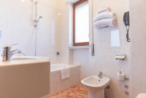 a white bathroom with a sink and a tub and a toilet at Hotel Riva Del Sole in Giovinazzo