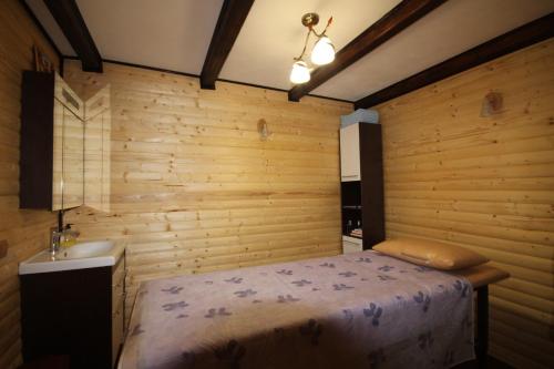 a bedroom with wooden walls and a bed and a sink at Prutets Guest House in Tatariv