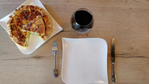 a table with a plate of pizza and a glass of wine at L'Amalgam' in Ainay-le-Vieil