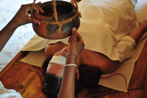 a woman sitting on a table holding a pot at Back of beyond - Wellness Retreat in Tangalle