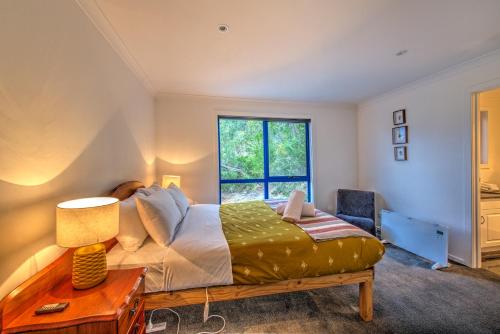 Un dormitorio con una cama y un escritorio y una ventana. en Blue Gum Retreat, en Coles Bay