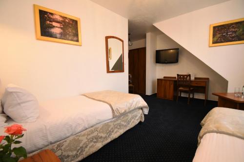 a hotel room with two beds and a desk at Kraina Jezior in Ostróda