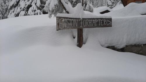 a sign in the snow next to a pile of snow at Pension Fürhapter mit Bio- Bauernhof in Sankt Jakob in Defereggen