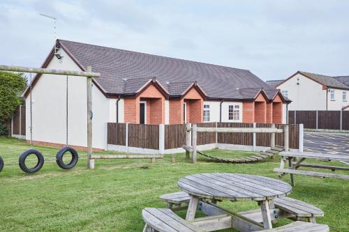 a group of picnic tables in a yard with a building at The Appleby Inn Hotel in Appleby Magna