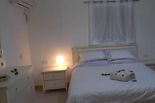 um quarto com uma cama branca e uma janela em צימרים שירת הכוכבים em Mitzpe Ramon