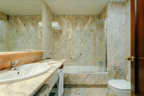 a bathroom with a sink and a tub and a toilet at Hesperia Vigo in Vigo