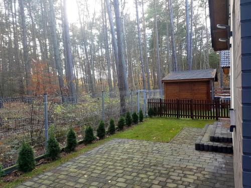 a backyard with a fence and a cabin with trees at Dom na Skraju in Łukęcin