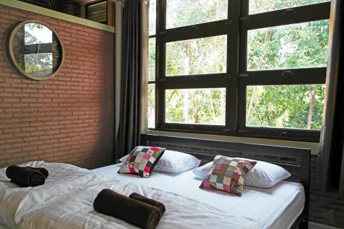two beds in a bedroom with two windows at บ้านก้ามปู อุทัยธานี in Ban Nong Nam Khan