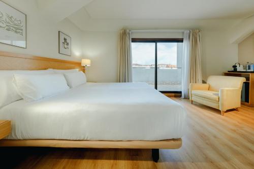 a bedroom with a large white bed and a chair at Hesperia Vigo in Vigo
