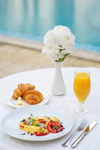 a table with a plate of food and a glass of orange juice at Villa Le Premier - Maestro in Odesa