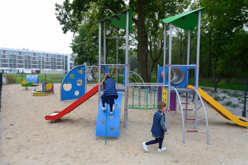 two children playing on a playground in the sand at Aparthotel Termy Uniejów in Uniejow
