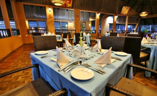a dining room with a blue table with napkins and servers at Maaha Beach Resort in Anochi