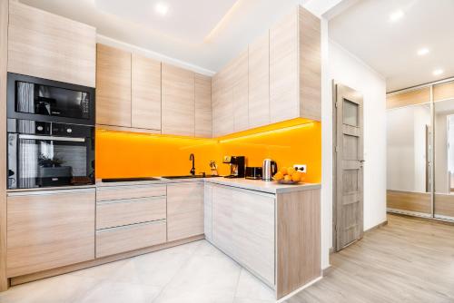 a kitchen with orange walls and wooden cabinets at Hamlet Old Town Apartment by TriApart in Gdańsk