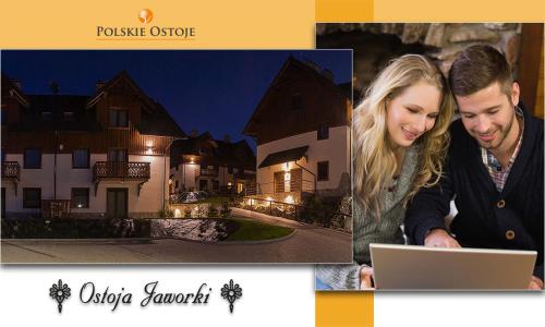 a couple looking at a laptop in front of a house at Apartament DOLOMITI in Jaworki