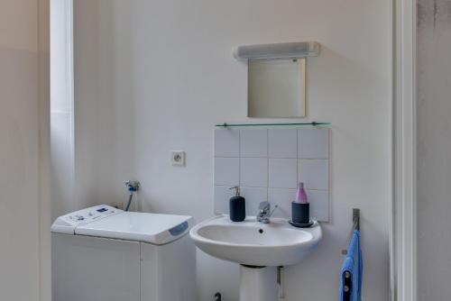 une salle de bain blanche avec un lavabo et un miroir dans l'établissement NOCNOC - Le Petit National, à Lille