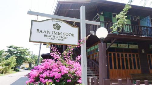 a sign for a beach resort with flowers in front of a building at Baan Imm Sook Resort in Chao Lao Beach