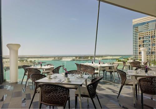 a restaurant with tables and chairs and a view of the ocean at Grand Hyatt Abu Dhabi Hotel & Residences Emirates Pearl in Abu Dhabi