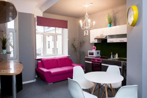 uma sala de estar com um sofá rosa, uma mesa e cadeiras em Urban Apartment em Riga