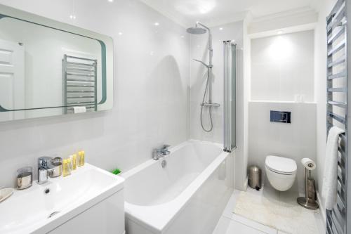 倫敦的住宿－Stunning 2-bed flat w/ garden patio in West London，白色的浴室设有浴缸和水槽。