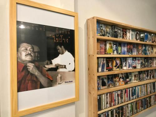 
a painting of a man sitting in front of a shelf full of books at 9TY hotel (ninety hotel) in Bangkok
