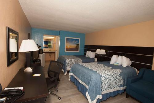 a hotel room with two beds and a desk at Days Inn by Wyndham Fort Myers Springs Resort in Estero