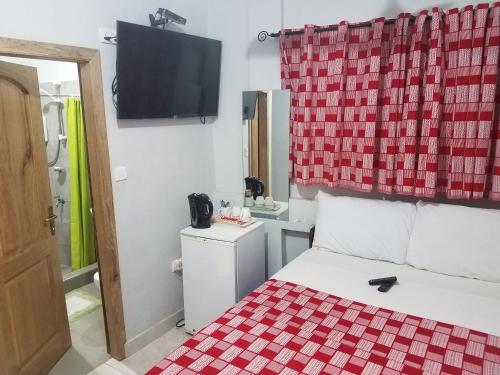 a room with a bed with a red and white checkered curtain at Sharp Guesthouse in Accra