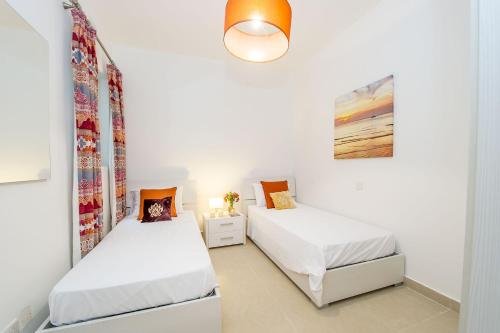 two beds in a room with white walls at Hillock Residence Apartments in Marsalforn