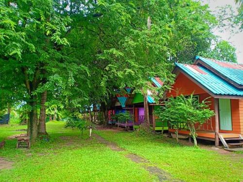 a house with a green yard next to a tree at Ko Yao Noi Sabai Bungalows in Ko Yao Noi