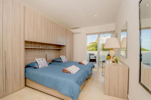a bedroom with a bed and a large window at Hillock Residence Apartments in Marsalforn