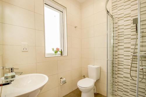 a bathroom with a sink and a toilet and a window at Hillock Residence Apartments in Marsalforn